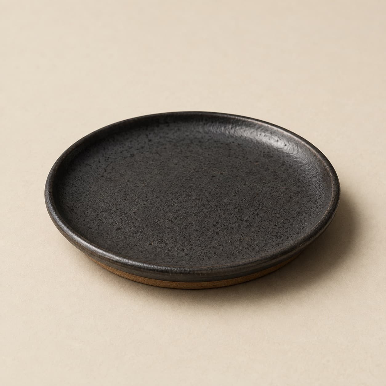 Bread Plate Ø14 — charcoal glazed stoneware with an unglazed clay foot ring.
