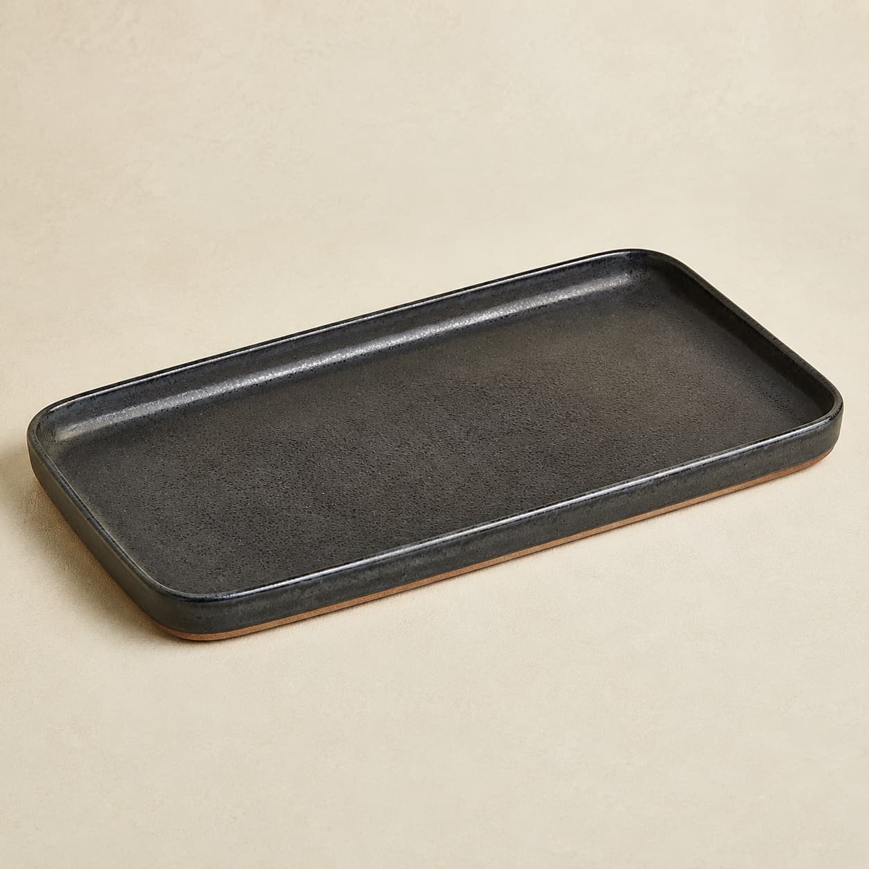 Serving Platter 34×22 — charcoal glazed stoneware with an unglazed clay foot ring.