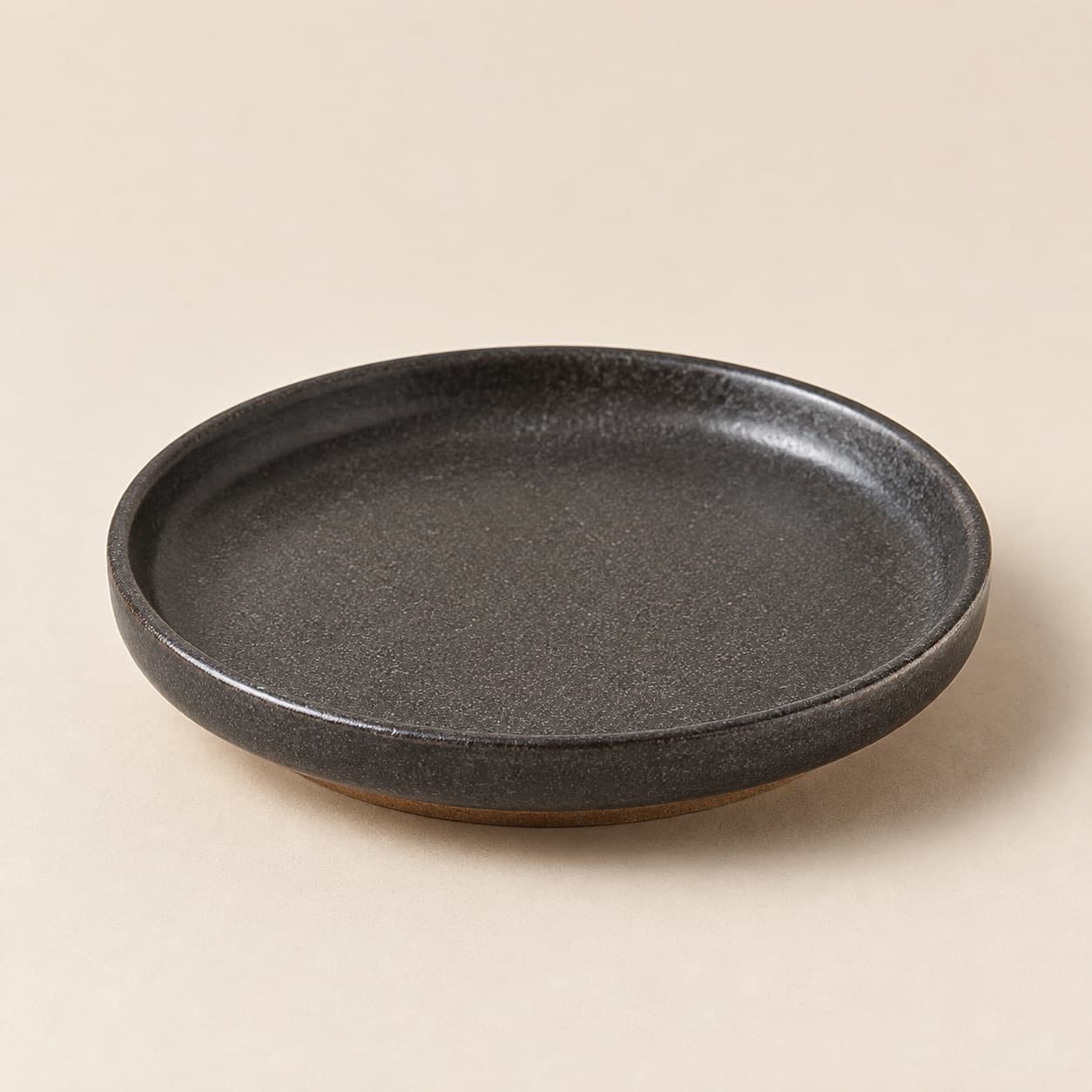 Side Plate Ø16 — charcoal glazed stoneware with an unglazed clay foot ring.